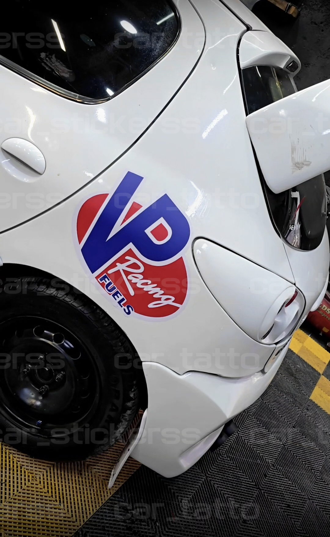 خودرو 206 که در مرکز دیتیلینگ در تهران است استیکر VP RACING که یک نوع سوخت خاص و گران قیمت است روی 206 نصب شده